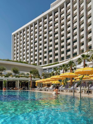 Un hotel con piscina, tumbonas y sombrillas.