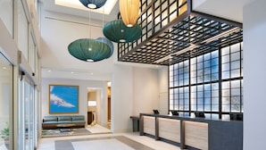 Eine moderne Hotellobby mit Empfangstresen, Sitzgelegenheiten und großen Fenstern.