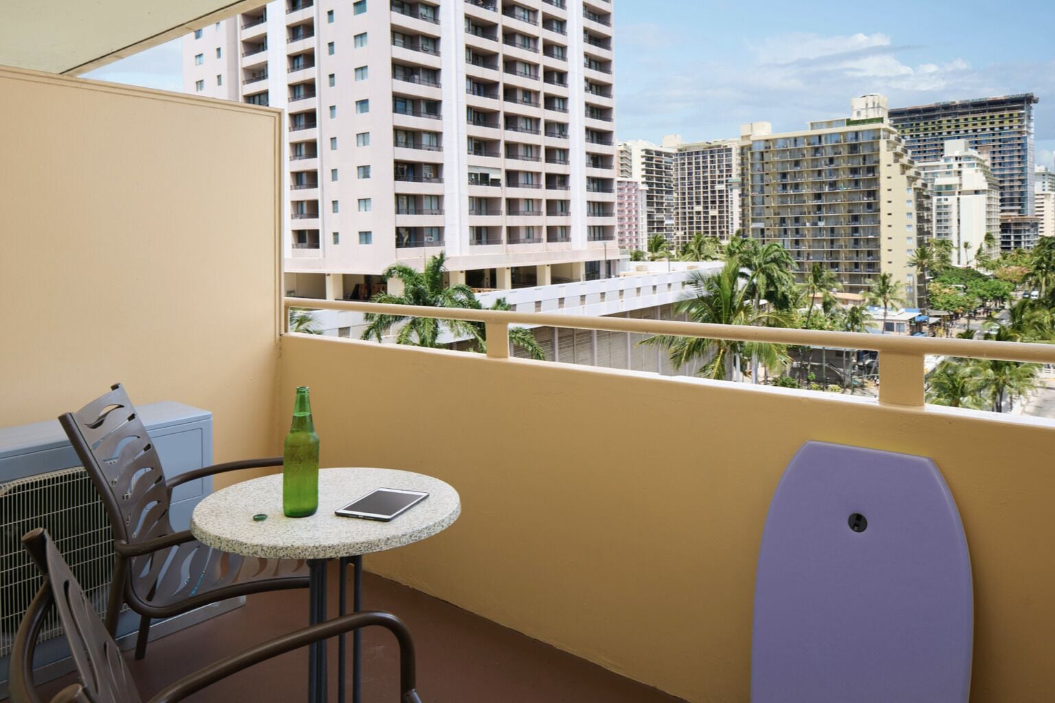 A balcony with a round table, a chair, a bottle, and a tablet.