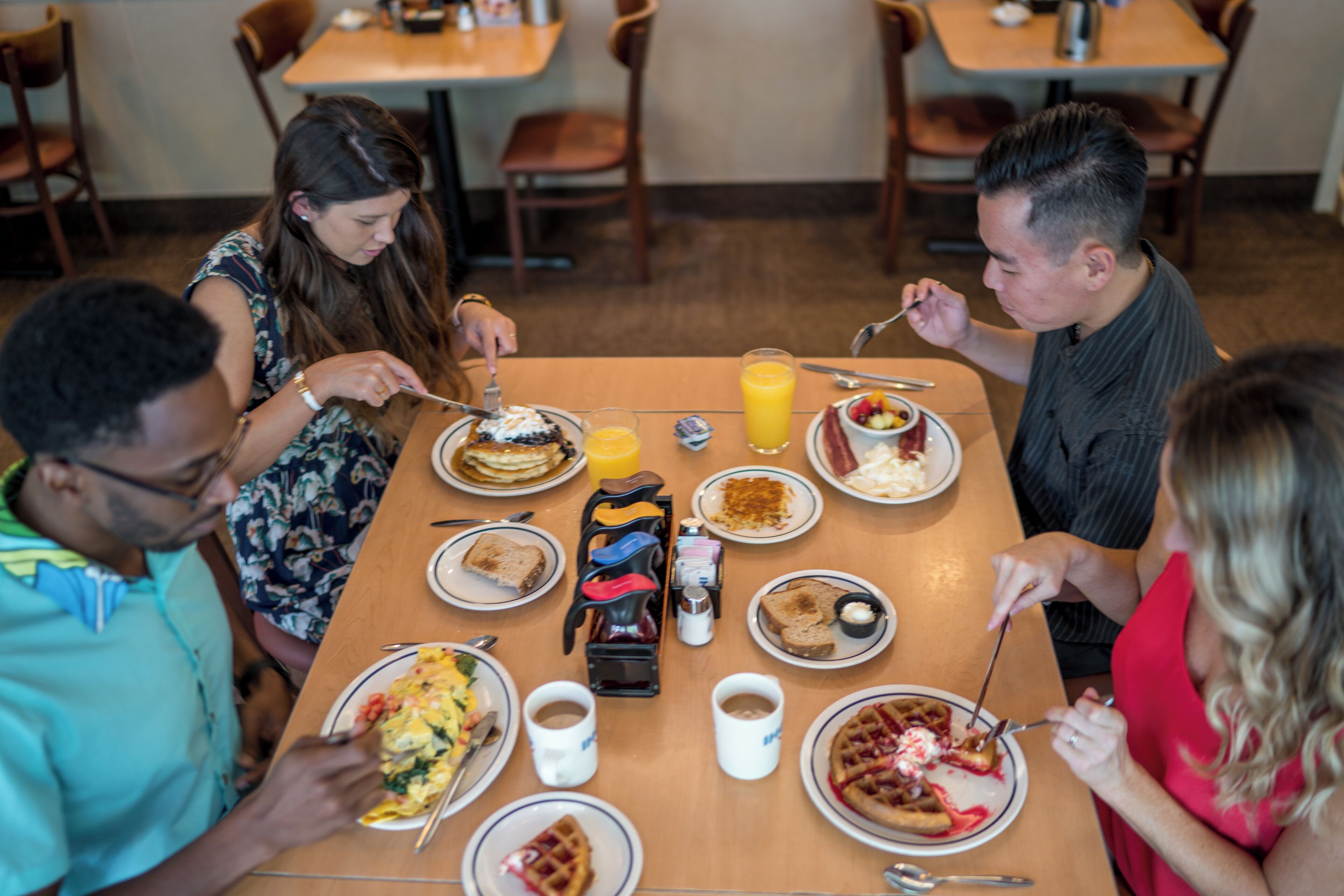 Un grupo de personas cenando en un restaurante con varios platos sobre la mesa.