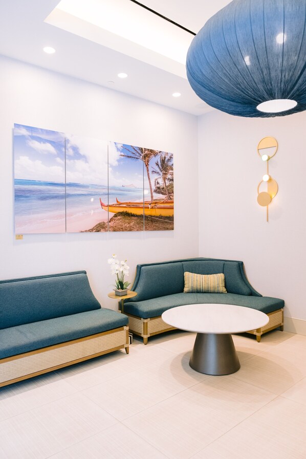 A modern interior with a green sofa, a round table, and wall art depicting a beach scene.