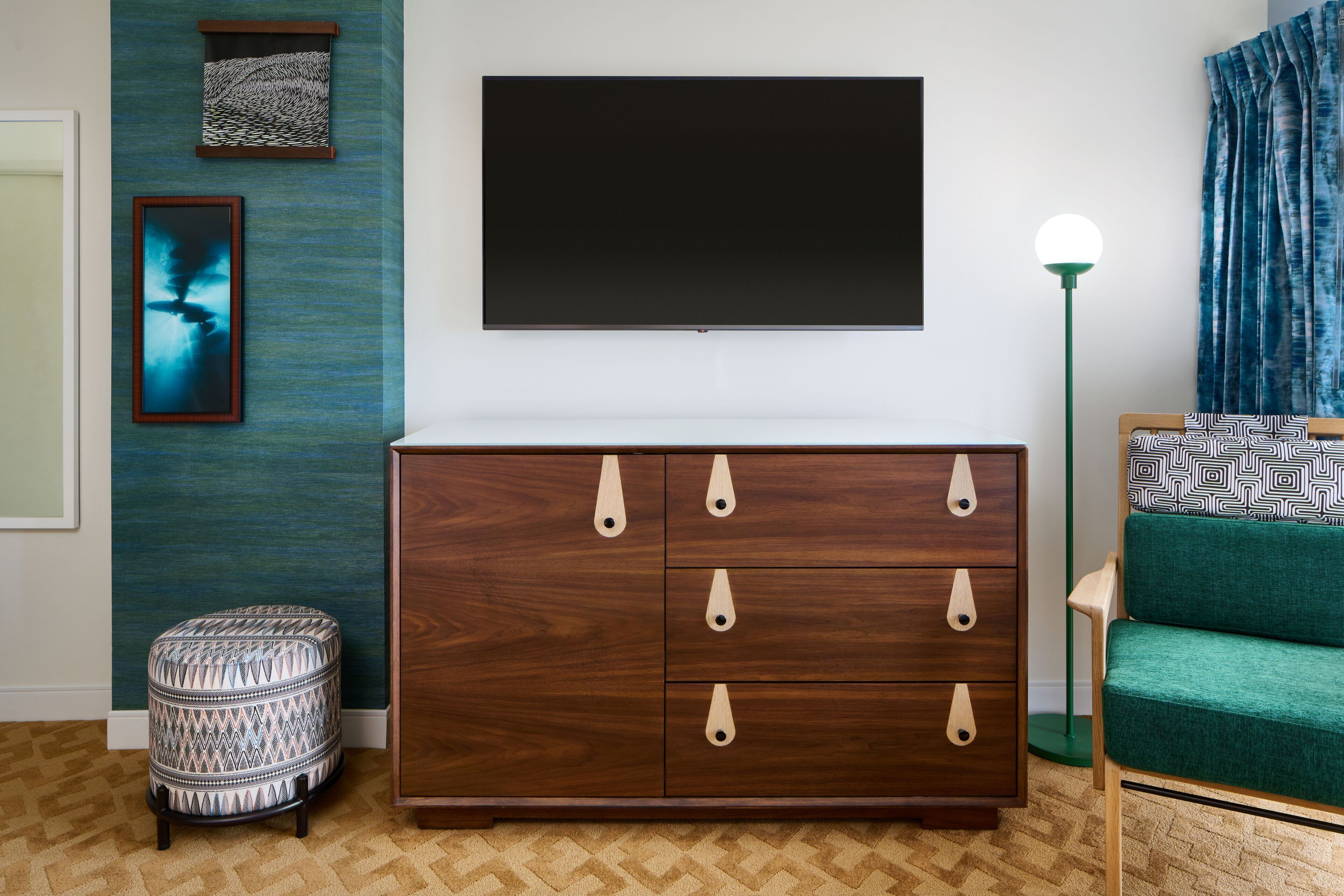 A modern living room with a dark wooden cabinet, a green sofa, and a flat-screen TV mounted on the wall.