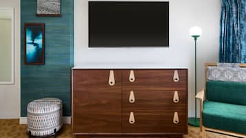 A modern living room with a dark wooden cabinet, a green sofa, and a flat-screen TV mounted on the wall.