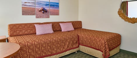 Une chambre dotée d’un canapé-lit deux places, d’une petite table et d’un miroir fixé au mur.