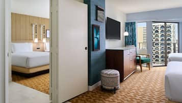 A hotel room with a bed, a desk, a chair, and a view of a building through a window.