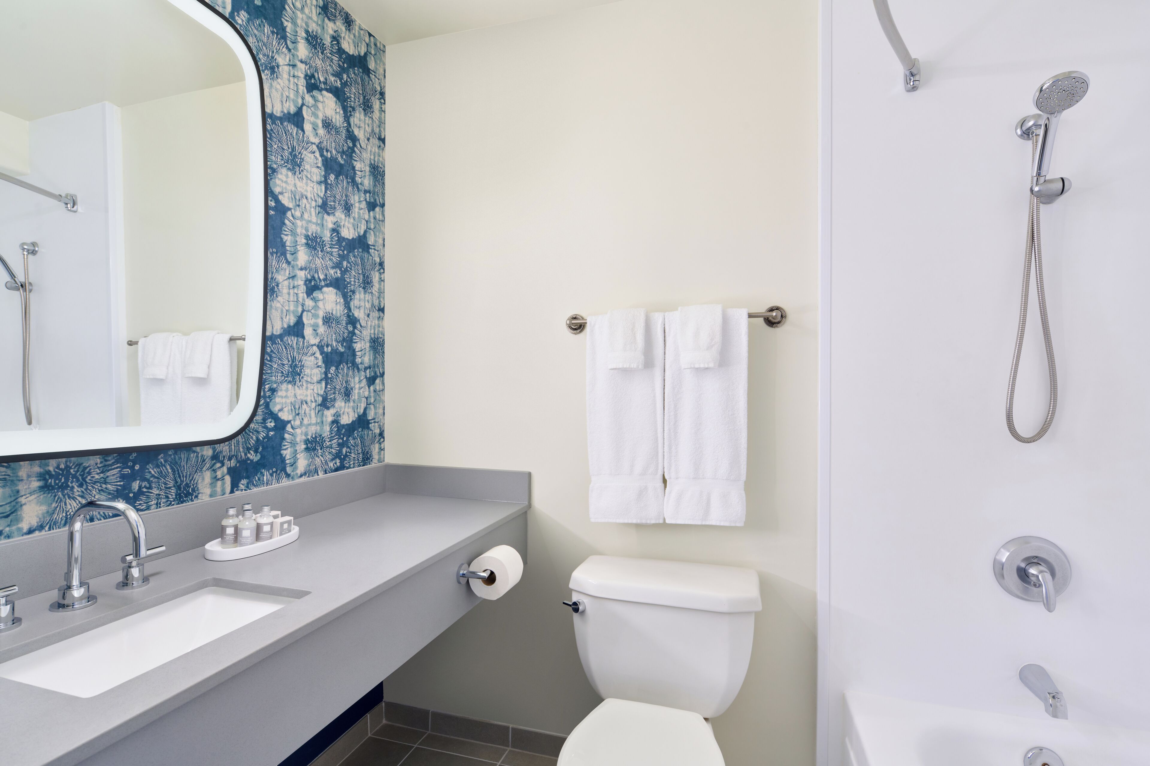 Une salle de bain moderne avec un lavabo blanc, des toilettes, une douche et un grand miroir.