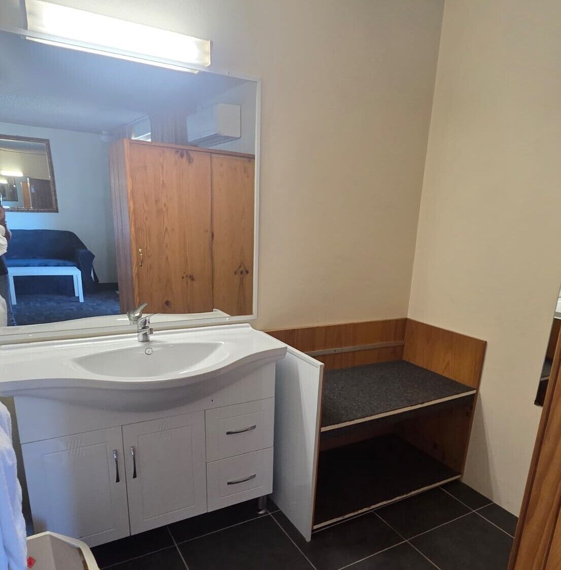 A bathroom with a white sink, mirror, and wooden cabinets.