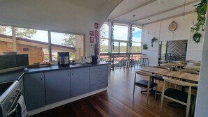 A modern kitchen with grey cabinets, a coffee machine, and a view of the outdoors through large windows. - Waterview Gosford Motor Inn (West Gosford)