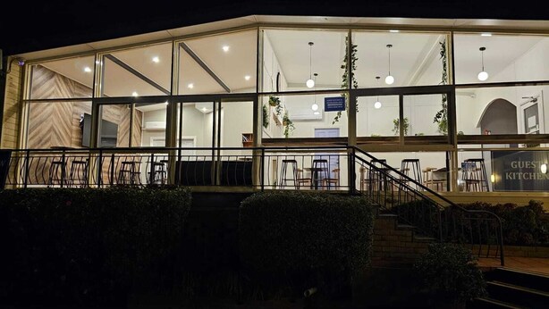 A modern building with large glass windows, a staircase leading to an upper level, and outdoor seating. - Waterview Gosford Motor Inn (West Gosford)