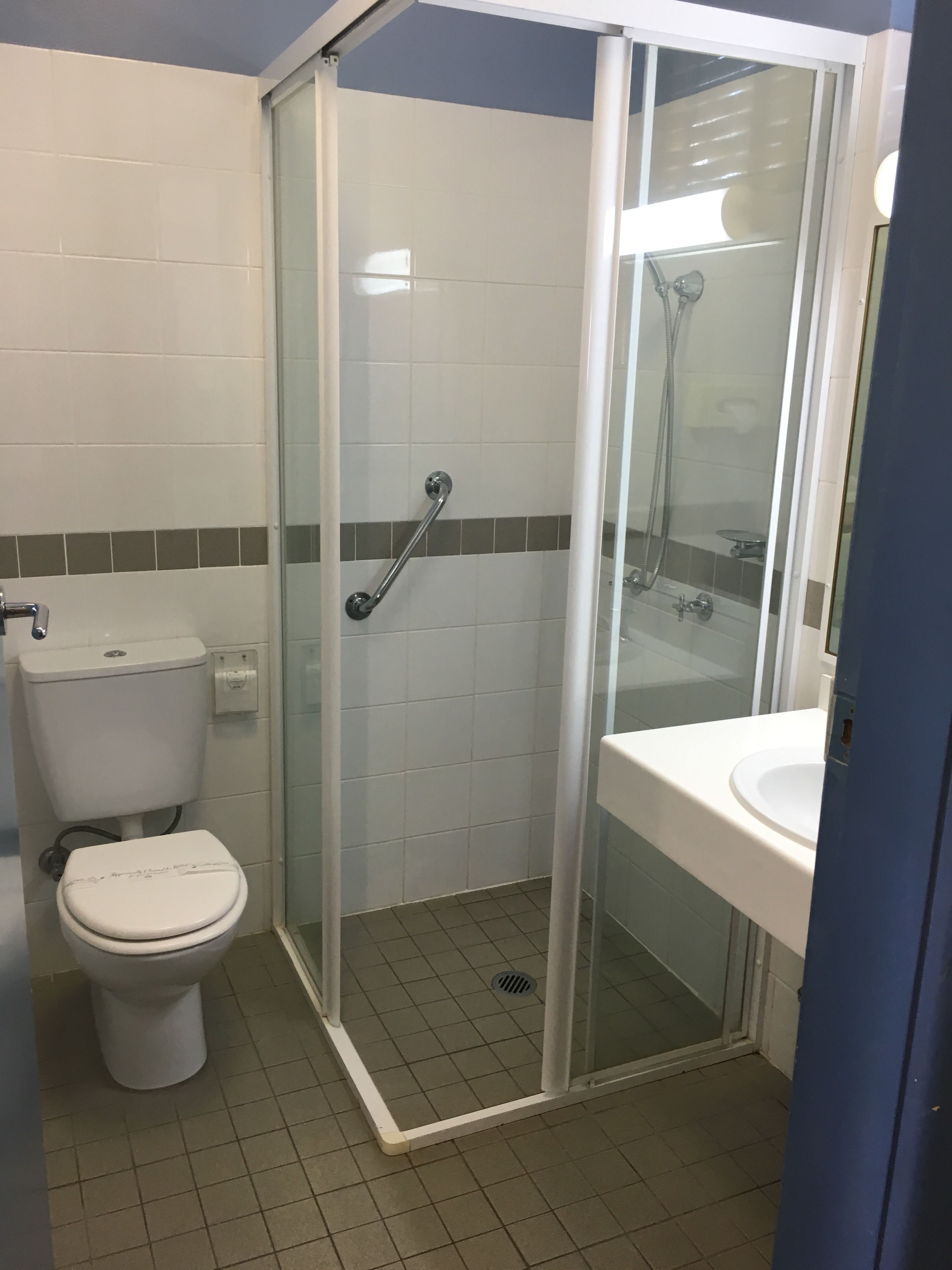 A bathroom with a toilet, a glass-enclosed shower, and a sink.