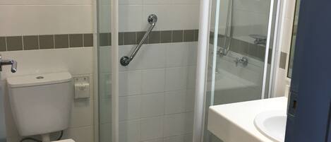 A bathroom with a toilet, a glass-enclosed shower, and a sink.