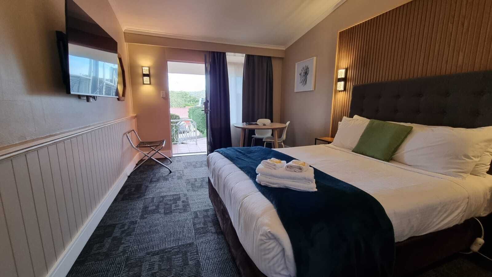 A hotel room with a bed, a desk, and a chair.
