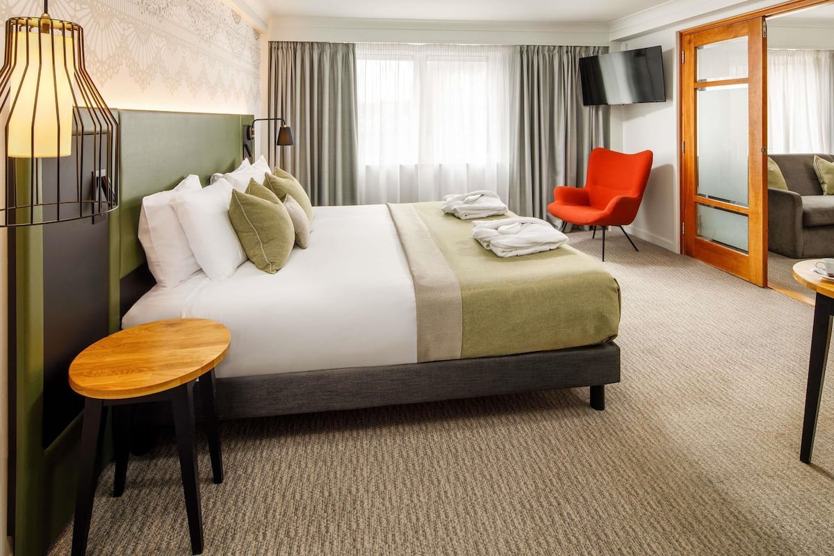 Une chambre d’hôtel avec un grand lit, un bureau, une chaise, une télévision et une porte coulissante.