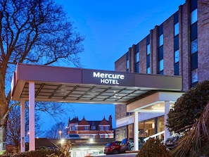 The Mercure Hotel with a prominent sign, a parking area, and a building in the background.
