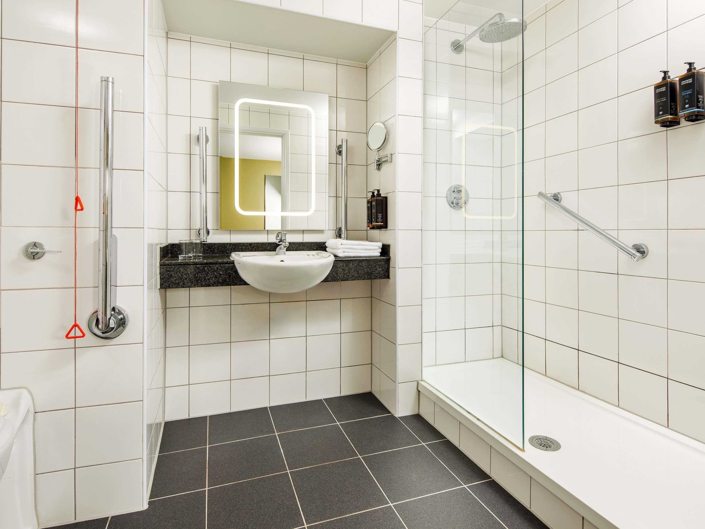 A modern bathroom with a white sink, mirror, and shower.