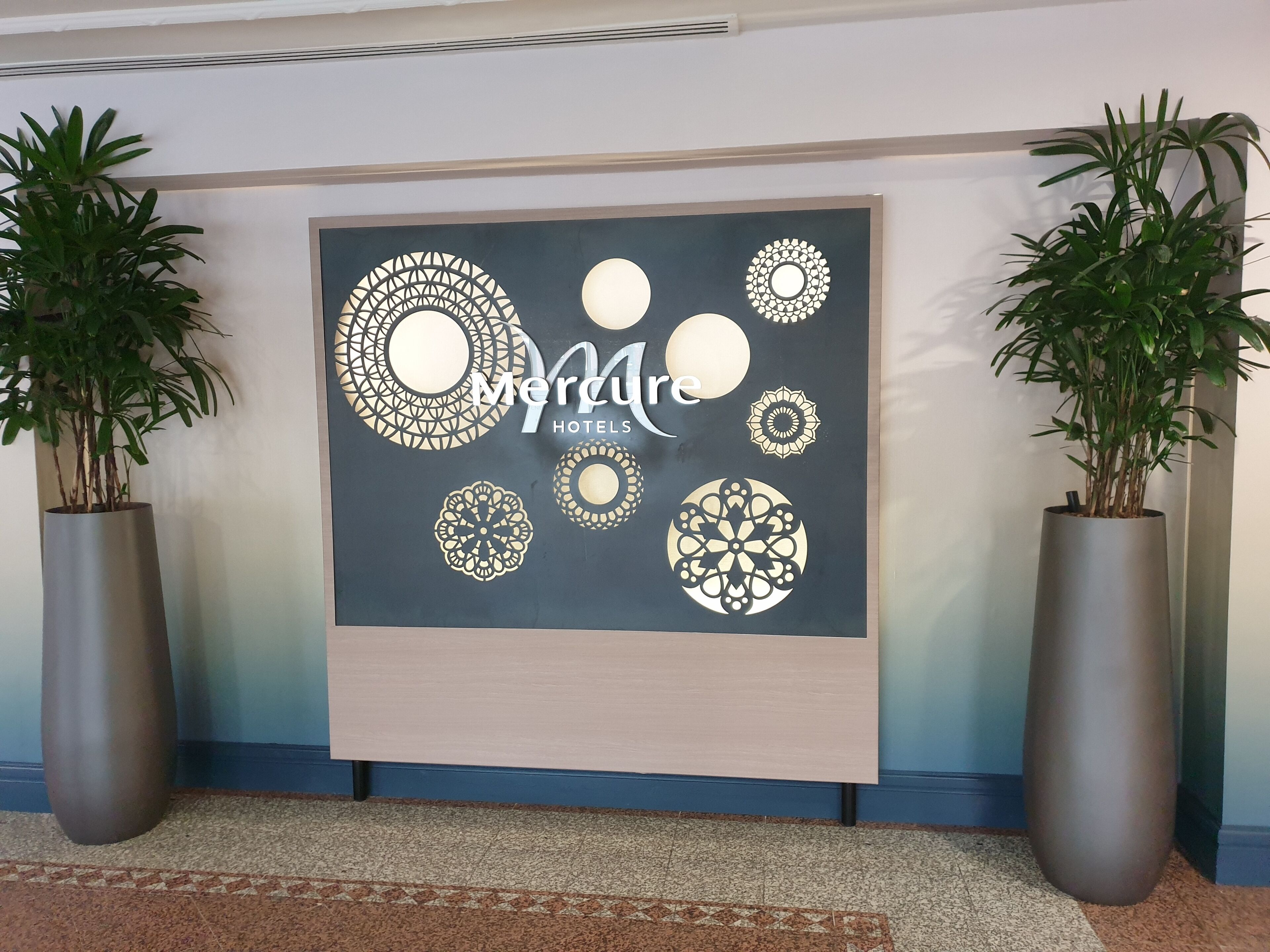 Una pared con un gran letrero de Mercure Hotels, rodeada de patrones circulares decorativos.