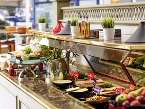 A buffet with various food items and condiments, including fruits, cheeses, and meats, displayed on a marble countertop.