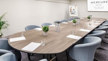 A conference room with a long table, chairs, water bottles, and a potted plant.