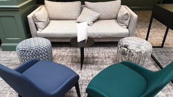A living room with a grey sofa, two patterned ottomans, and two chairs, one blue and one teal.