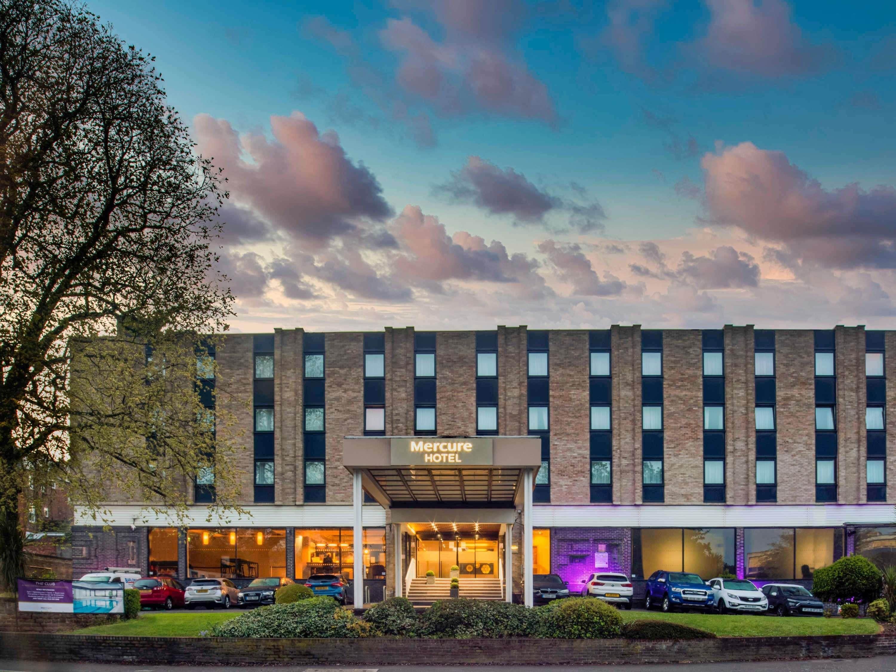 A hotel with a brick facade, multiple windows, and a sign reading 'Mercure HOTEL'.