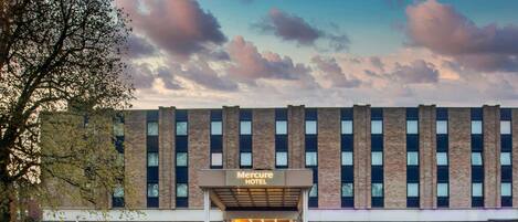 Un hotel con fachada de ladrillo, varias ventanas y un cartel que dice 'Mercure HOTEL'.