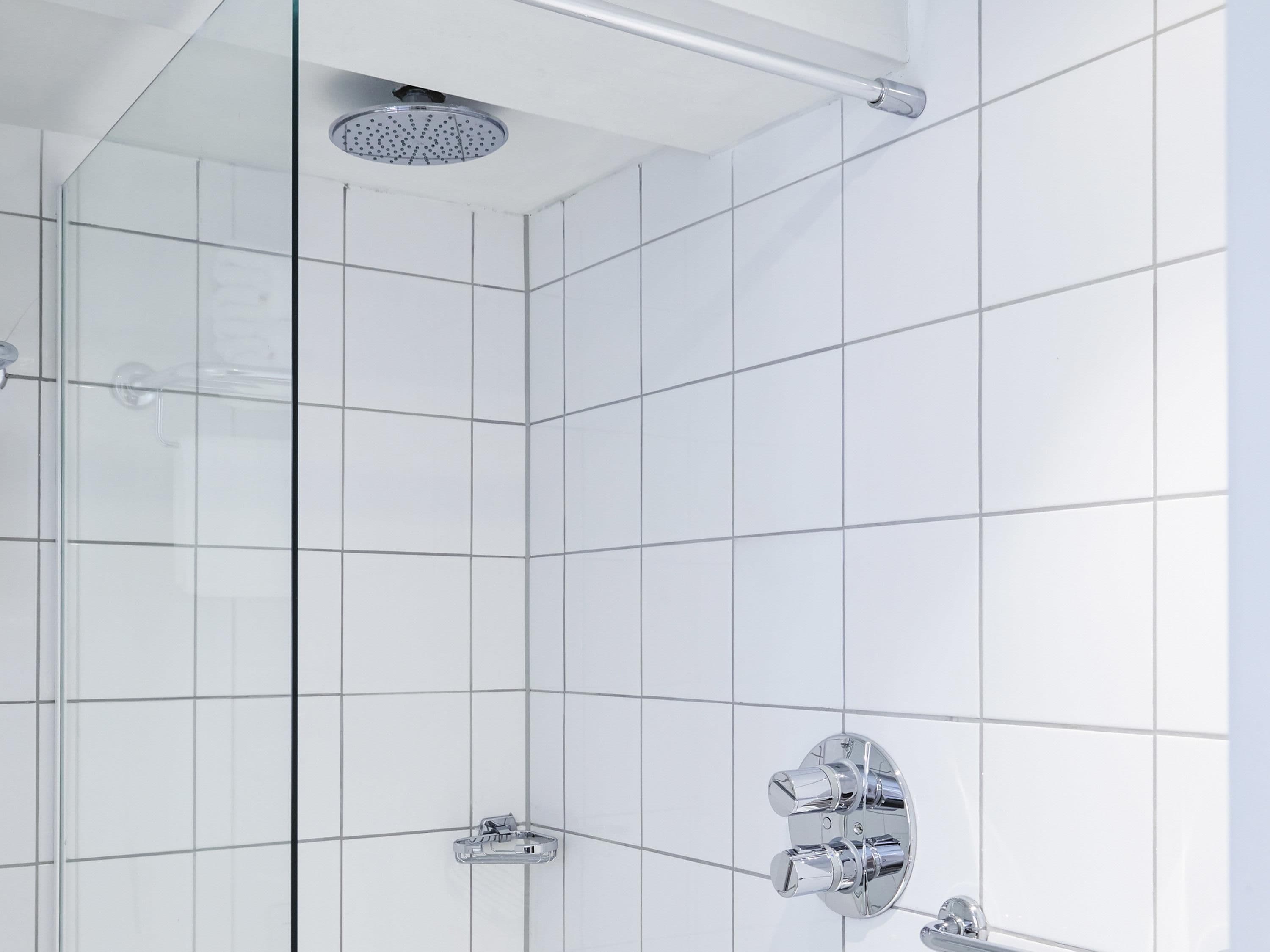 A modern shower with a handheld showerhead and a wall-mounted control panel.