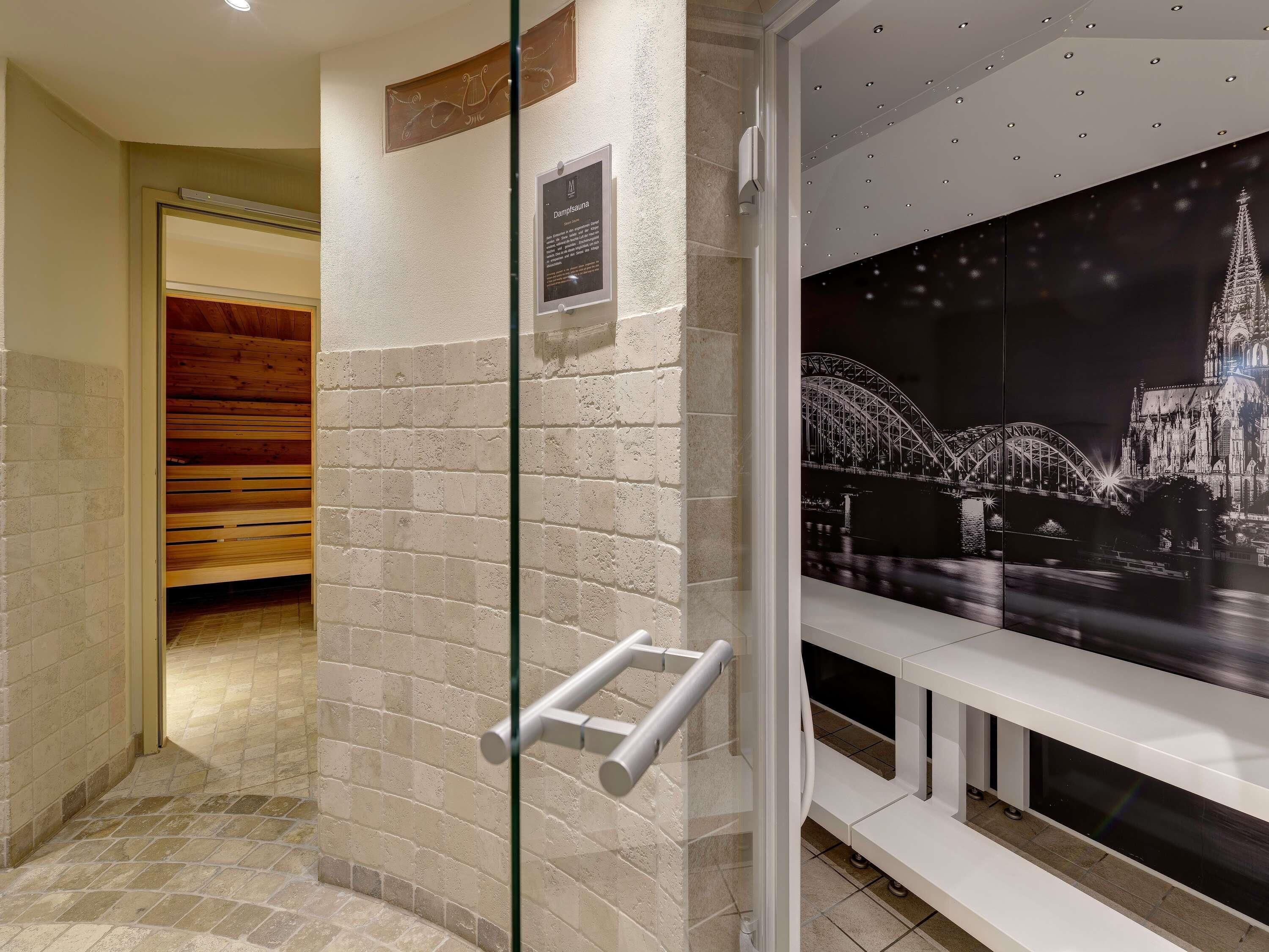 Une salle de bain moderne dotée d’une douche à parois de verre, d’un banc et d’un porte-serviettes fixé au mur.