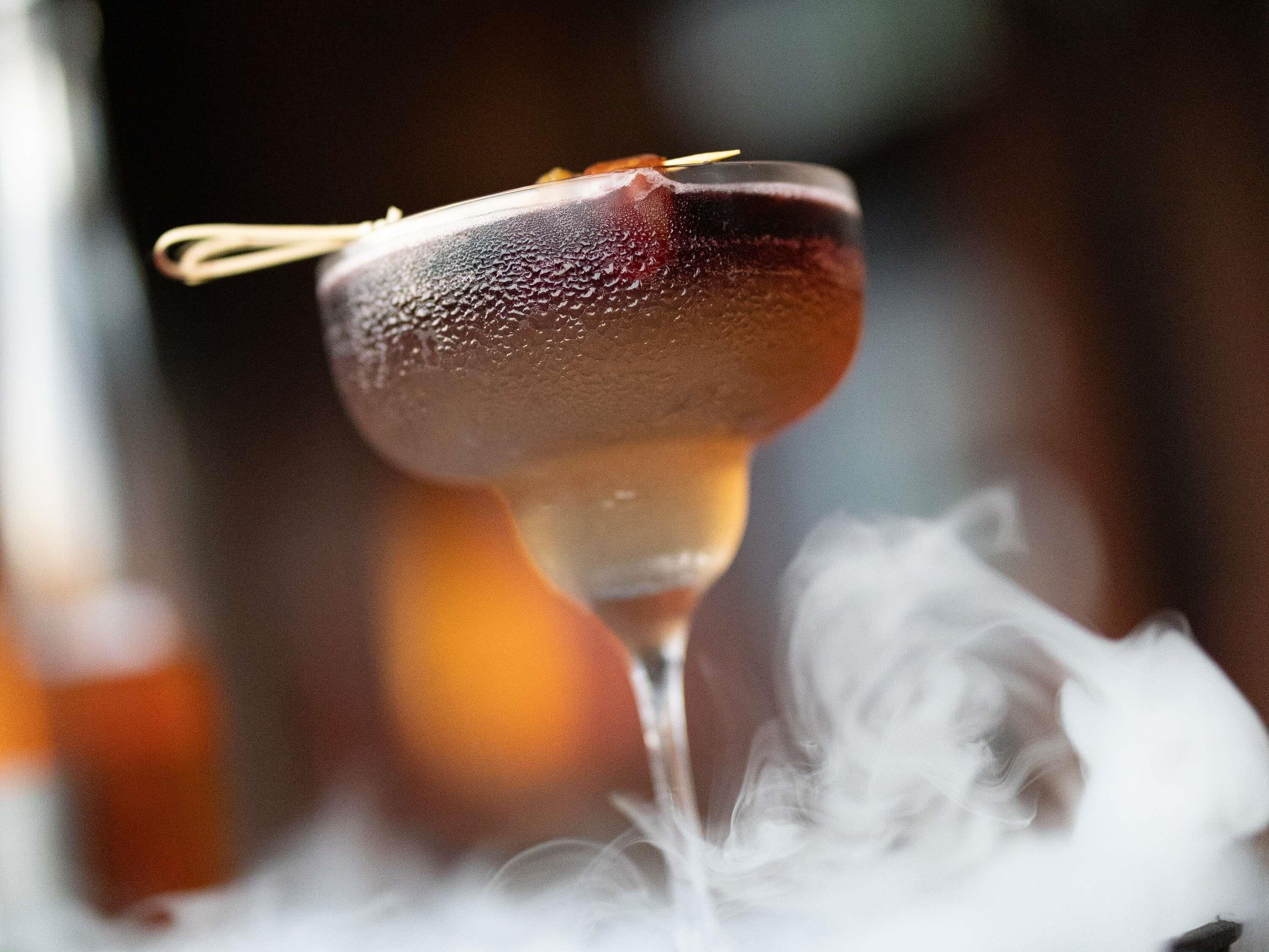 Un cocktail agrémenté d’une garniture, servi dans un verre à pied.