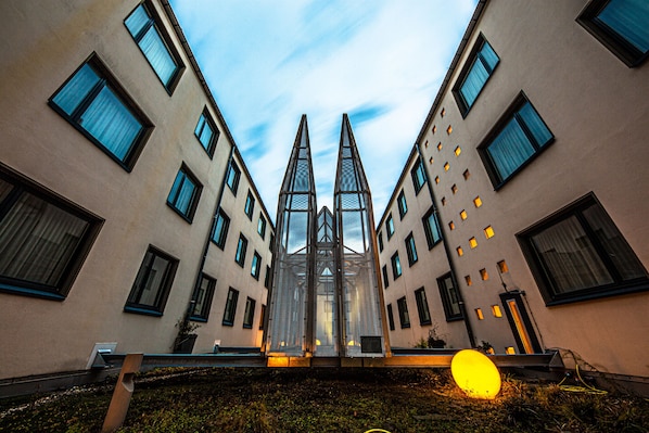 Un edificio moderno con fachada simétrica, múltiples ventanas y una estructura central de cristal.