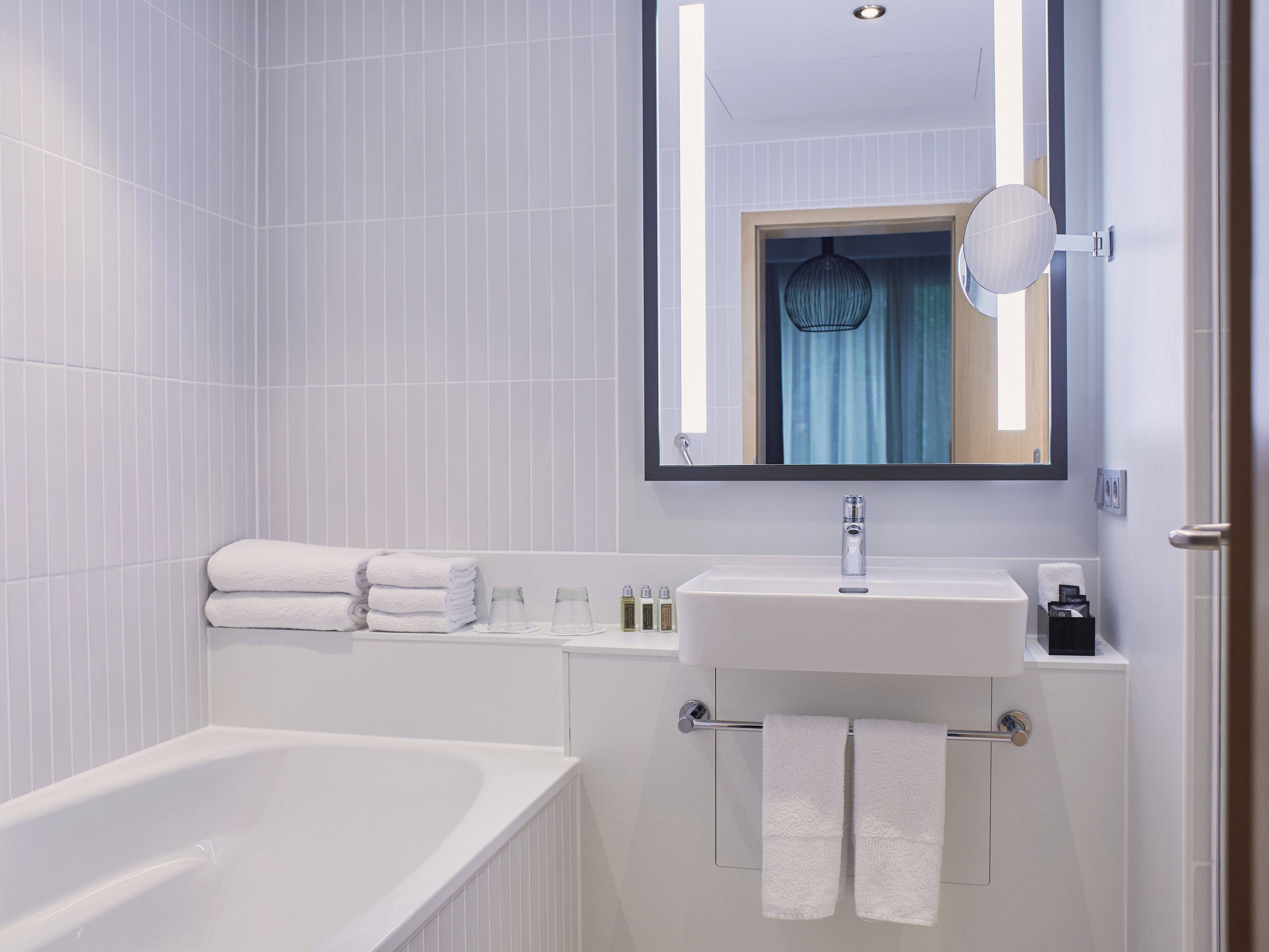 A modern bathroom with a bathtub, a sink, and a mirror.