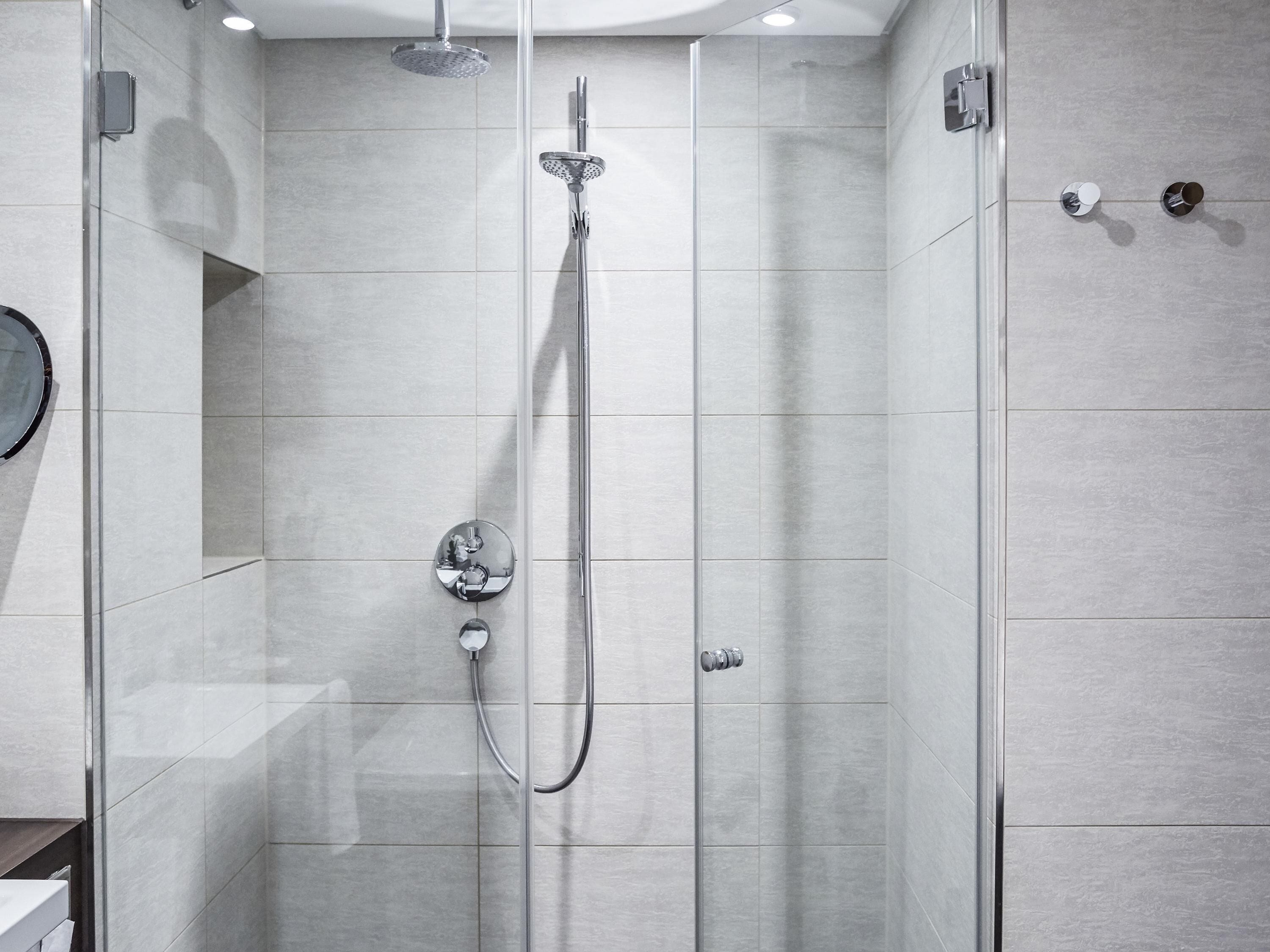A modern shower with a handheld showerhead, a wall-mounted faucet, and a control panel.