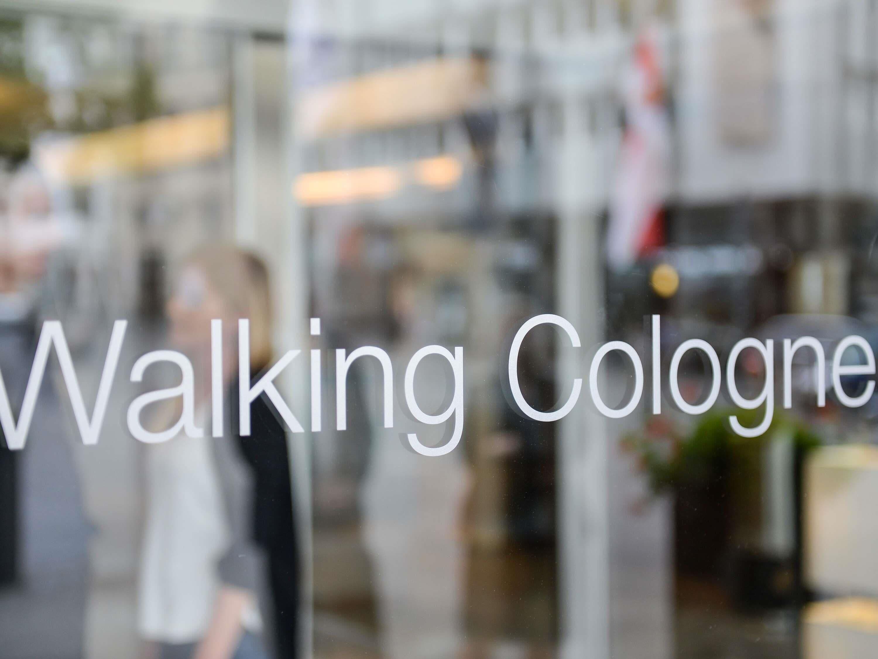 Vista desfocada de uma loja com a inscrição 'Walking Cologne' visível.