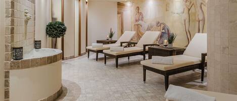 Un espacio de spa con sillones de masaje, una recepción y un mural con figuras clásicas.