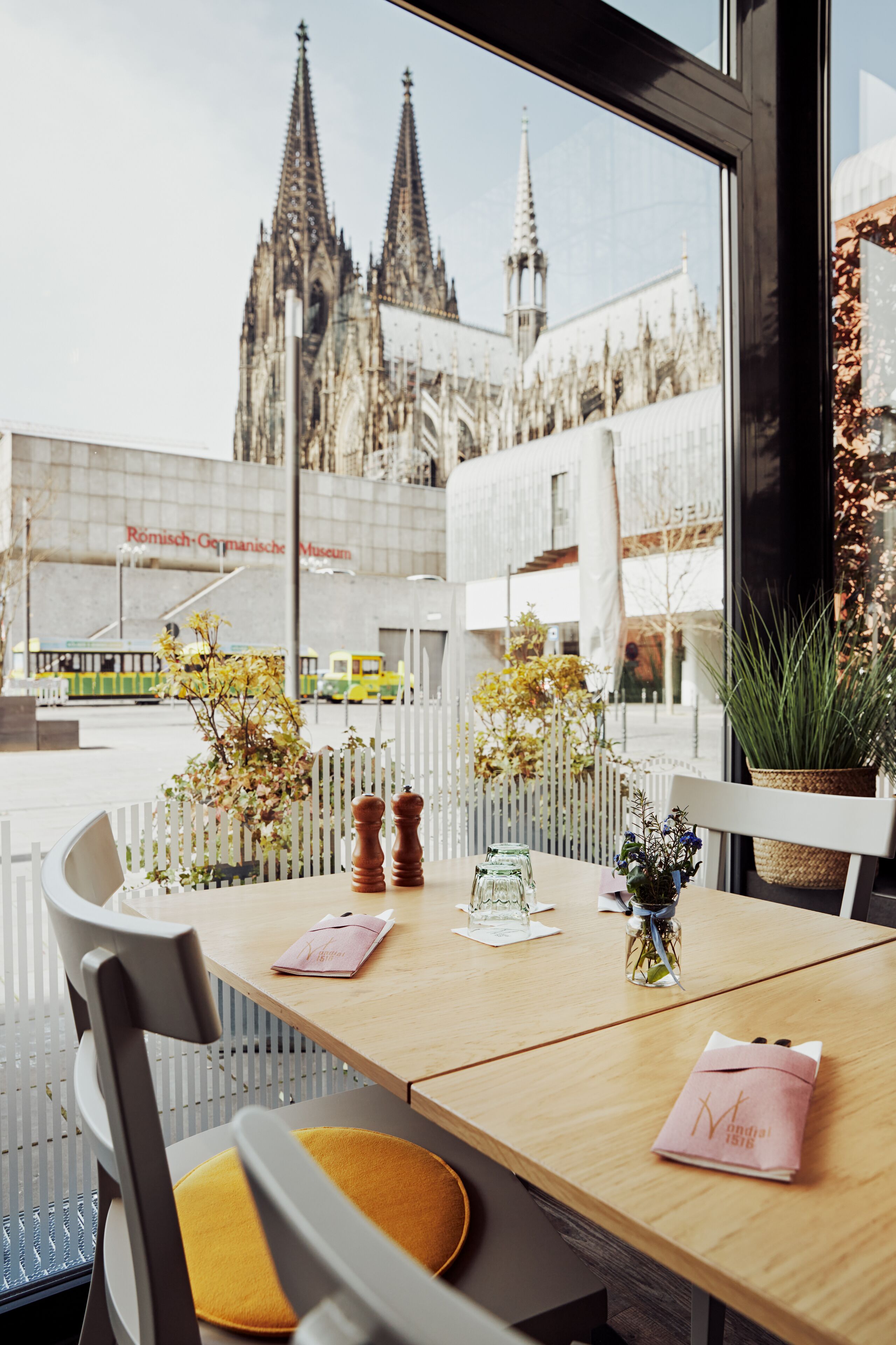 Una mesa con vistas a una catedral, una planta y un cojín amarillo.