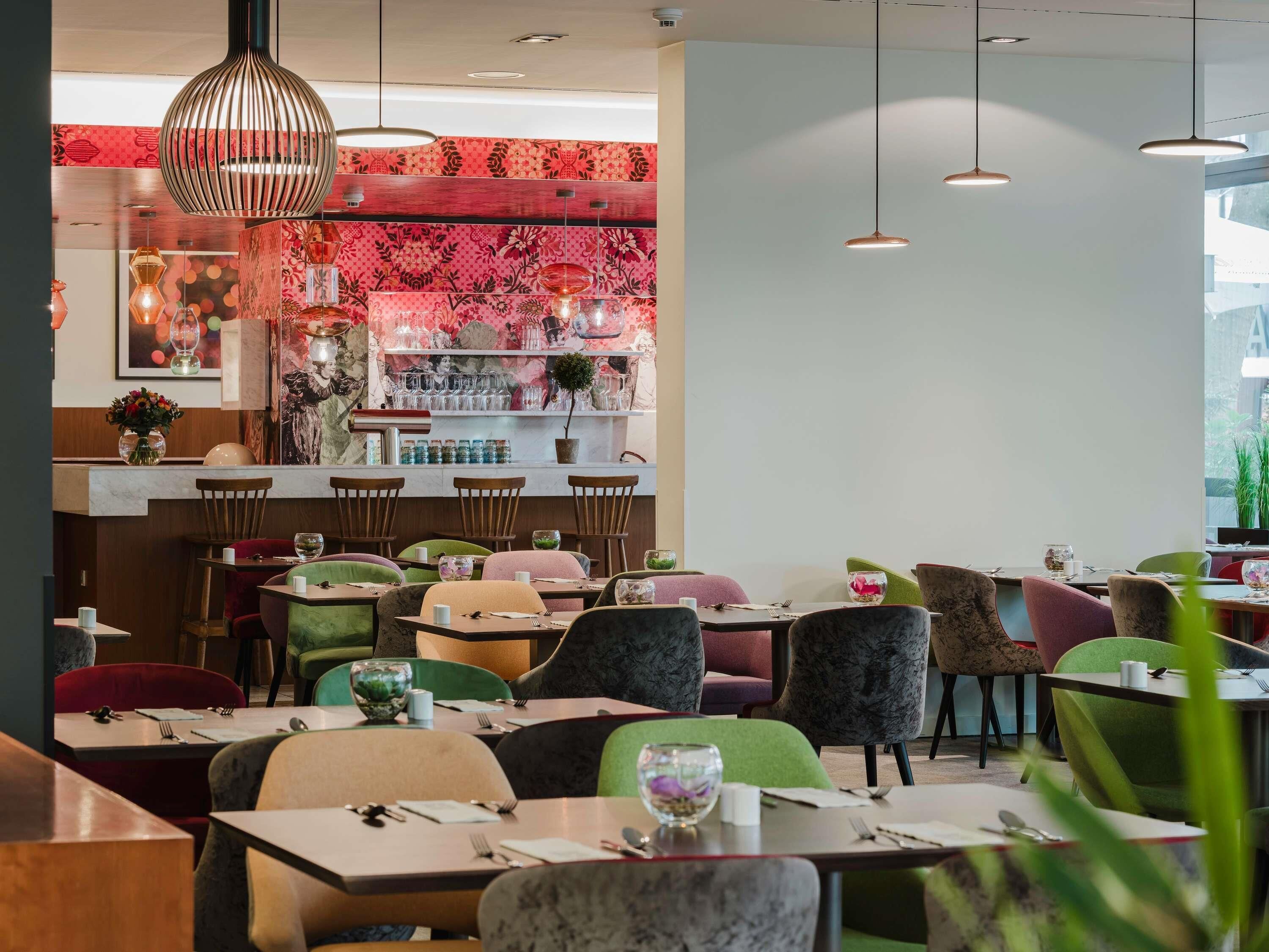 A restaurant interior with a bar area, multiple seating options, and pendant lighting.