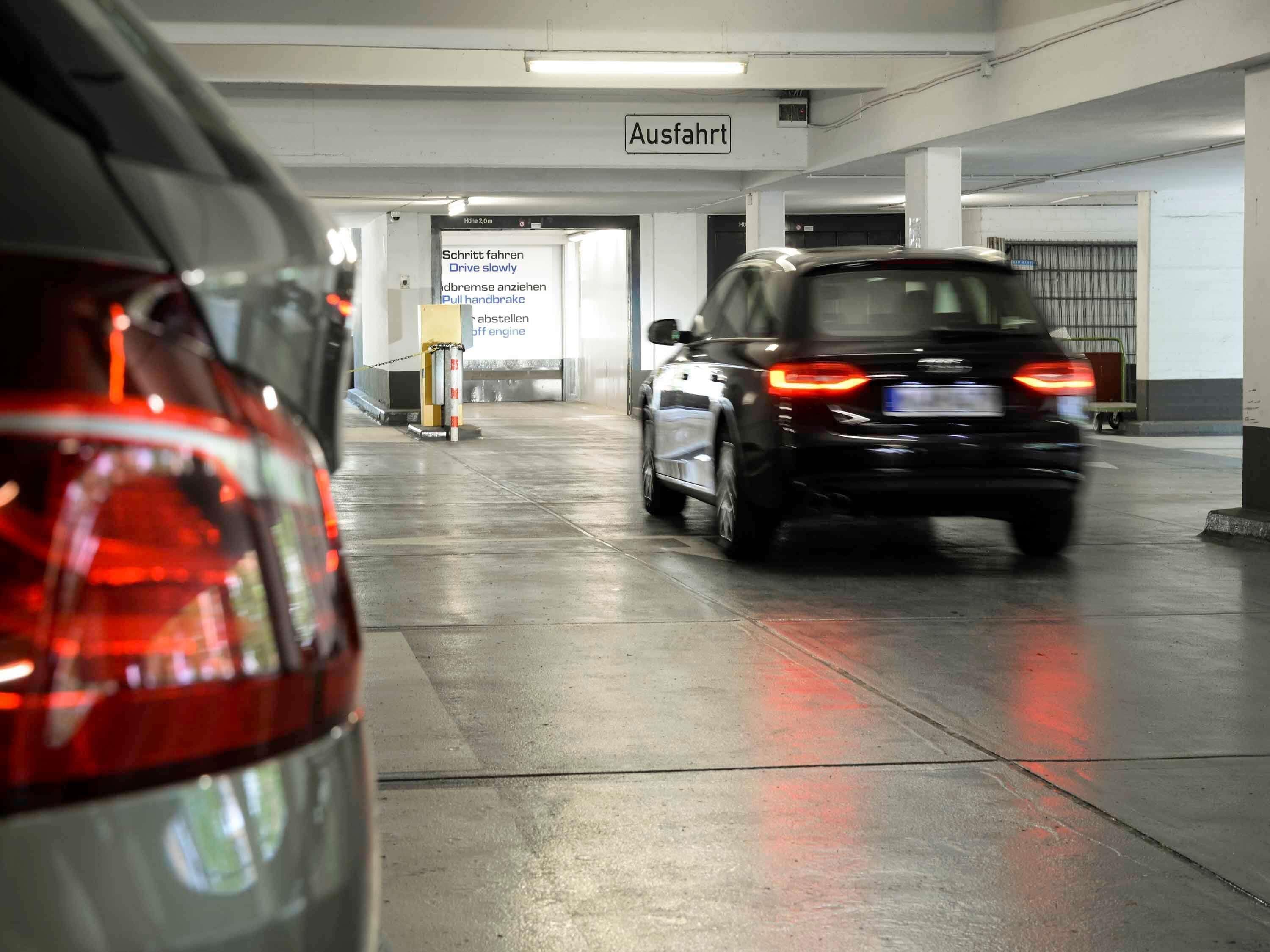 A parking garage with a car driving towards an exit.