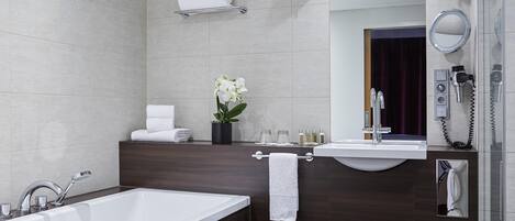 Un baño moderno con una bañera, un tocador con espejo, un perchero para toallas y un teléfono en la pared.