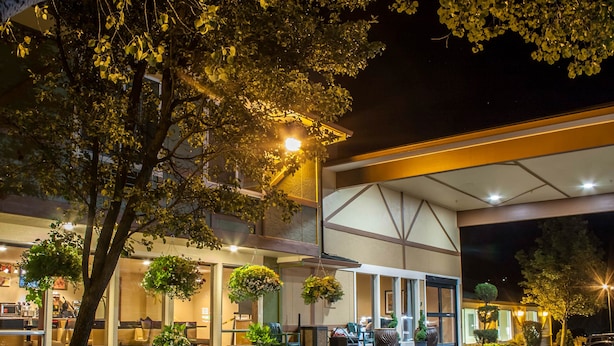 A hotel entrance with outdoor seating, potted plants, and a well-lit facade.