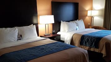Habitación de hotel con dos camas, cada una con cabecera, mesitas de noche, lámparas y cubrecamas azules.