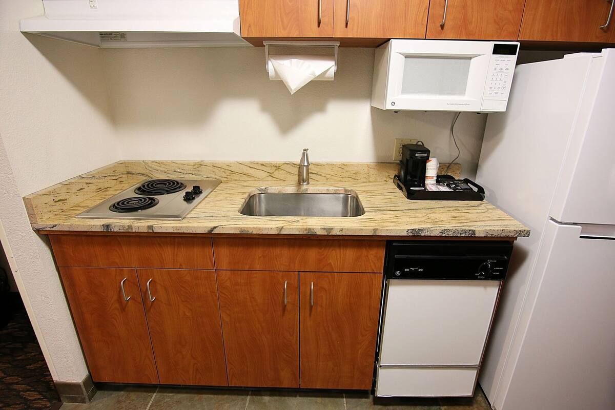 Una cocina compacta equipada con estufa, pileta, microondas y lavavajillas.