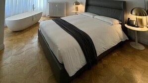 Un dormitorio moderno con una cama grande, una bañera integrada, un lámpara en el techo y un radiador.