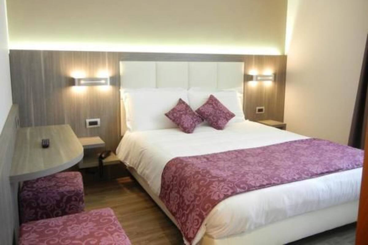 A hotel room with a bed, bedside tables, a chair, and a nightstand.