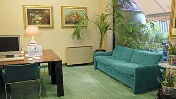 Une pièce comprenant un bureau, un ordinateur, une chaise, un canapé et des plantes en pot.