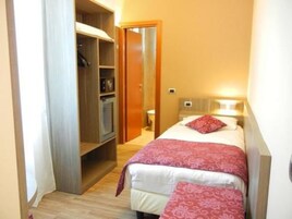 Un corridoio stretto conduce a una camera da letto con un letto, un comodino e un armadio.