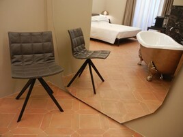 A bathroom with a bathtub, a bed, and two chairs.