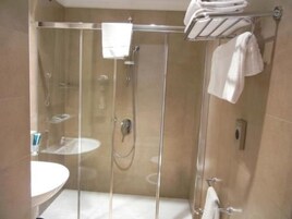 Een douchecabine met glazen wanden, een handdoekhouder erboven, een wastafel en een toilet.