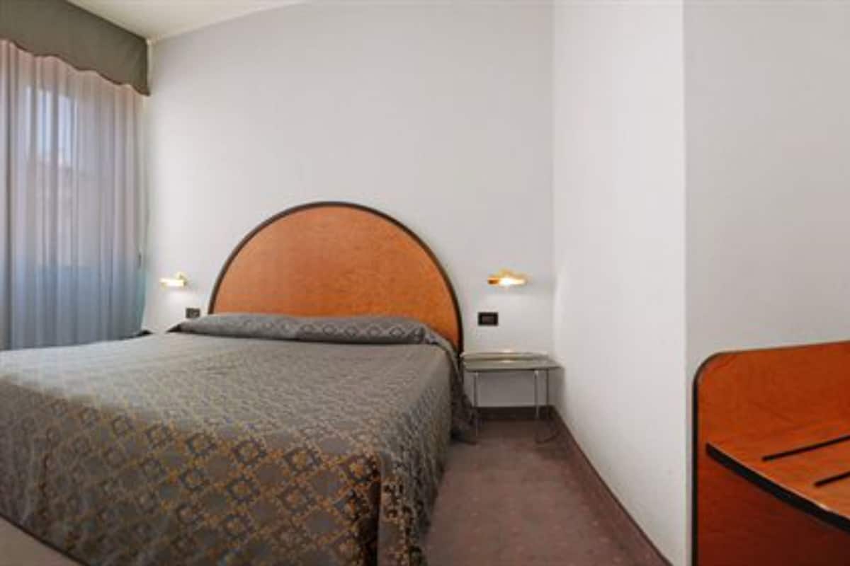 A hotel room with a bed, bedside tables, and a small seating area.
