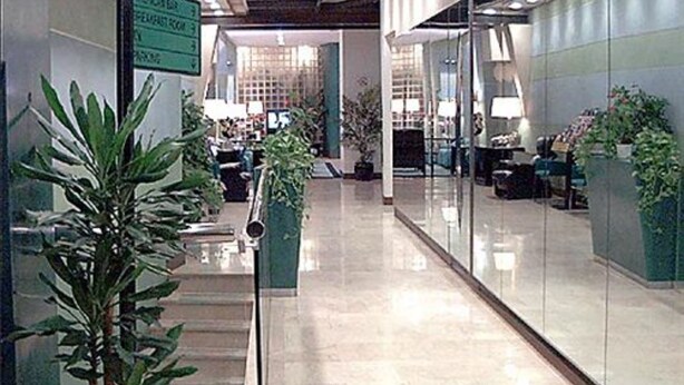 Un pasillo con paredes de vidrio, plantas en macetas e indicación de estacionamiento.