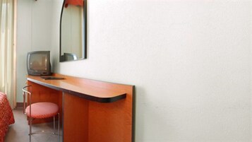 A room with a wooden desk, a television, and a red chair.