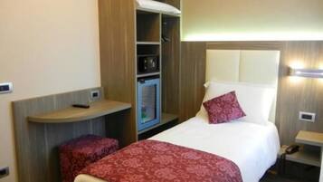 A compact hotel room with a bed, a small desk, a wardrobe, and a built-in microwave.